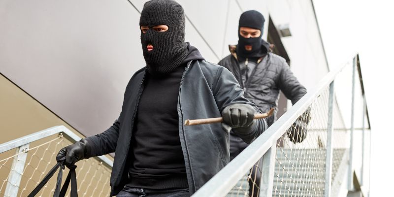 Two burglars in masks exiting a building