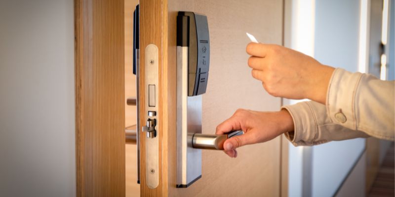 Person opening door with a keycard that has a access control device attached